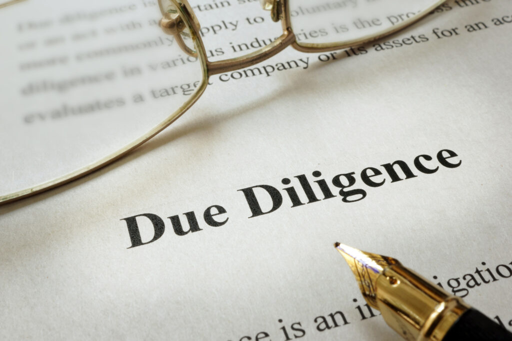 closeup of a document with the printed words "due diligence" and a fountain pen nearby